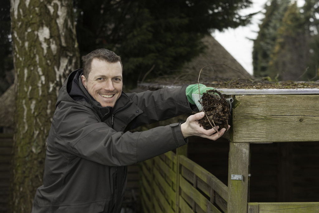 smiling man cleaning the gutters